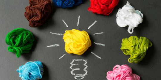 image of different colour crumpled up tissues in a circle with a yellow in the center with chalk lightbulb stem using tissue as the lightbulb