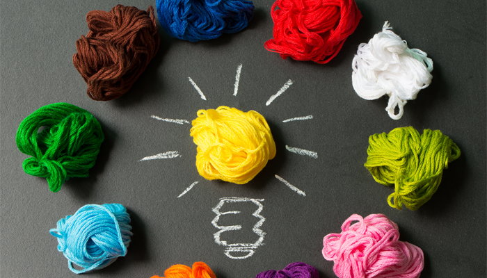 image of different colour crumpled up tissues in a circle with a yellow in the center with chalk lightbulb stem using tissue as the lightbulb