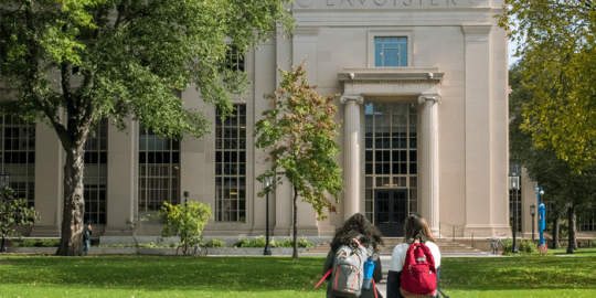 image of 2 students walking towards a university signifying safety and why social media background checks can help