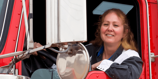 female trucker driver in front seat smiling after landing job due to driving record abstracts