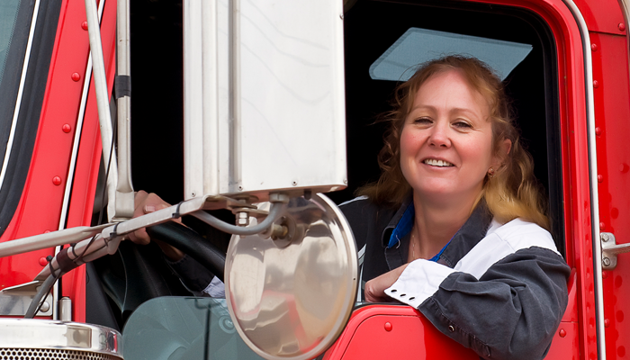 female trucker driver in front seat smiling after landing job due to driving record abstracts