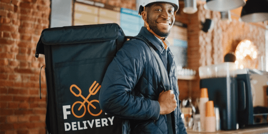 image of a smiling african american young man carrying a food delivery bag as a side hustle