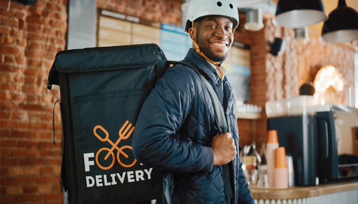 image of a smiling african american young man carrying a food delivery bag as a side hustle