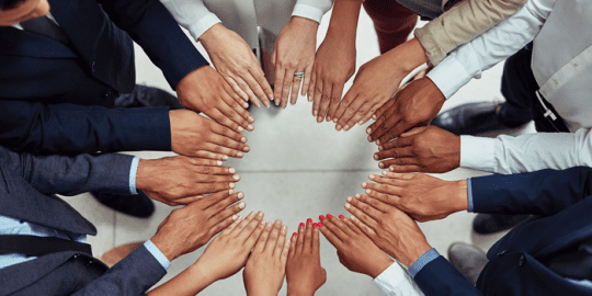 diverse group of professionals all putting their hands in a circle