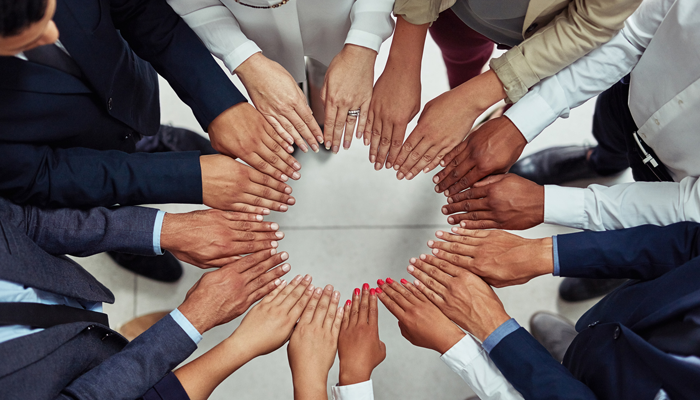 diverse group of professionals all putting their hands in a circle