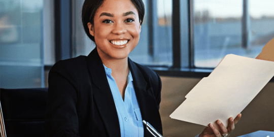 image of professional african american women smiling holding up new hire background checks in folder