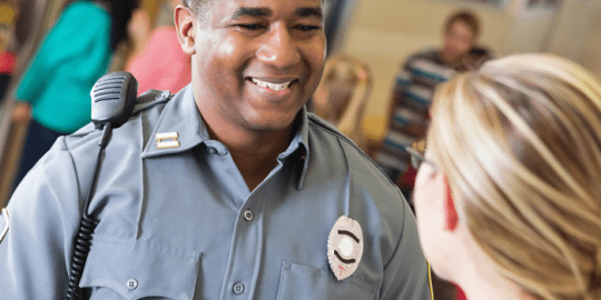 security guard smiling to a woman. This image signifies a security guard position